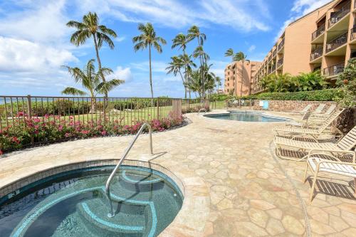a resort pool with chairs and palm trees at Maalaea Banyans 214 in Wailuku