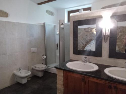 a bathroom with two sinks and a toilet and a mirror at Murisengo Country Houses in Murisengo