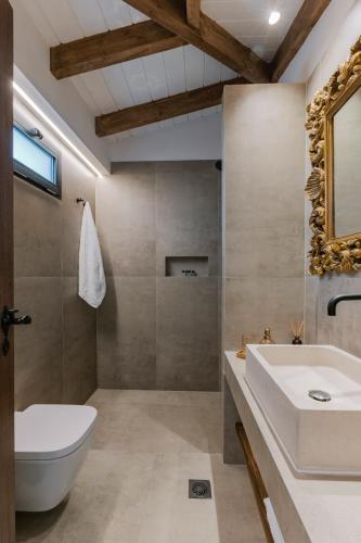 a bathroom with a sink and a toilet and a mirror at La Casetta della Nonna in Lardos