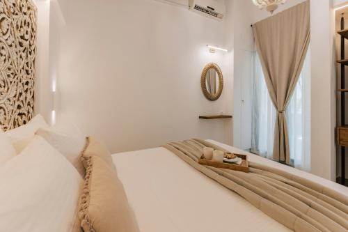 a bedroom with a white bed and a mirror at La Casetta della Nonna in Lardos
