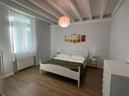 ein weißes Schlafzimmer mit einem Bett und einem großen Fenster in der Unterkunft Residenza Giuglini, a 10 min dal mare in Fano