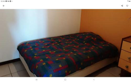 a bed with a colorful comforter in a bedroom at Gîte du Causse in Boussac