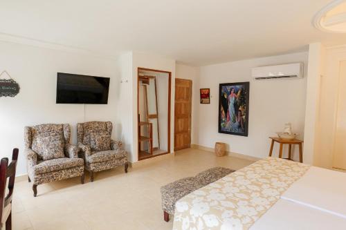 a bedroom with a bed and two chairs at Hotel Kartaxa in Cartagena de Indias