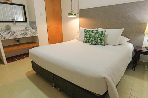a large white bed in a room with a bathroom at Hotel Kartaxa in Cartagena de Indias