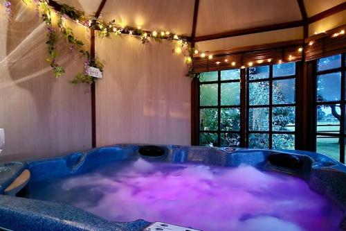 a large tub with purple water in a room with windows at Stud House in Private Country Estate near Bruton in Gillingham