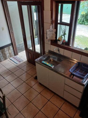 a kitchen with a sink and an open door at Pousada das Palmeiras in Garopaba