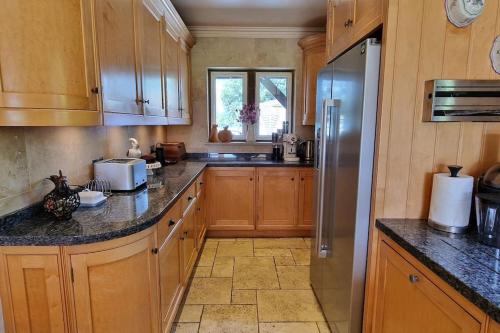 a kitchen with wooden cabinets and a stainless steel refrigerator at Stud House in Private Country Estate near Bruton in Gillingham
