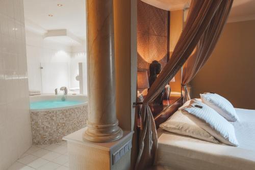 a bedroom with a bed and a tub in a room at Van der Valk Theaterhotel Almelo in Almelo