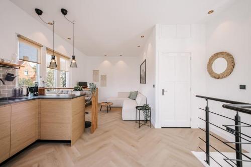 a kitchen and living room with white walls and wooden floors at Bella Beach House in Zandvoort