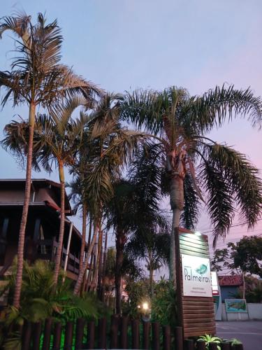 a palm tree in front of a house with a sign at Pousada das Palmeiras in Garopaba