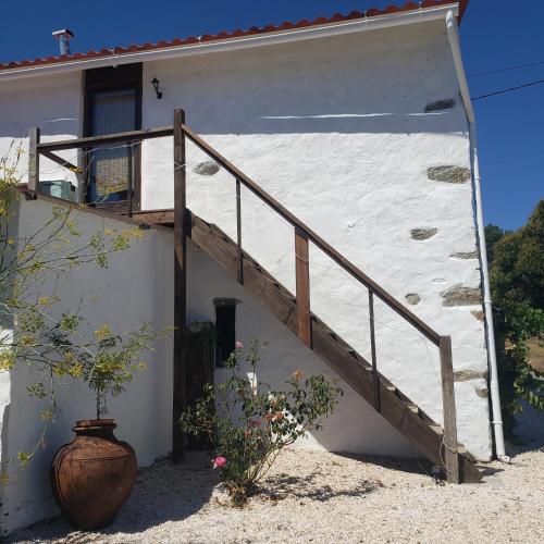 a white building with a wooden staircase next to it at Casa Hortensia in Cardigos