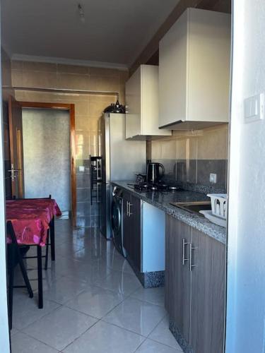 a kitchen with a table and a counter top at Appart situé au centre de Martil ,moderne près de la plage ,de l'aéroport Tetouan et vue sur lac in Martil