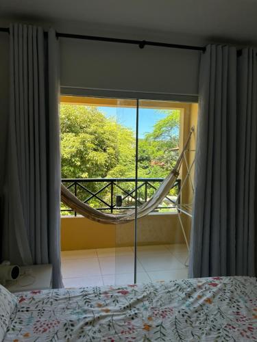 ein Schlafzimmer mit einem Bett und einem großen Fenster in der Unterkunft Flat - Condomínio Brisa da Serra - Gravatá in Gravatá