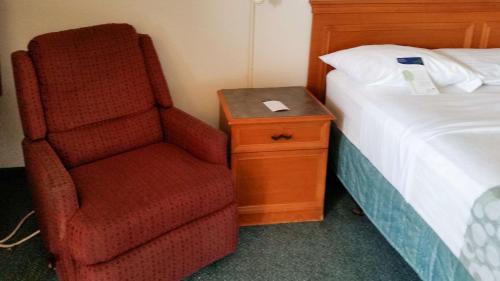 a bedroom with a red chair next to a bed at Motel 6-Monroe, LA in Monroe
