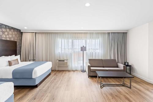a hotel room with a bed and a couch at Best Western Plus Montreal East in Montréal