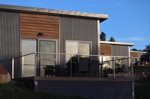 a house with a large balcony with chairs on it at Hygge Eco Cabins Beautiful New Cabins with Amazing Views in Jindabyne