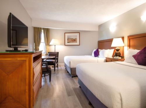 a hotel room with two beds and a flat screen tv at Coast Parksville Hotel in Parksville
