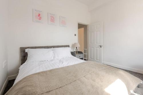 a white bedroom with a large bed with white sheets at 5min to Huddersfield Royal Infirmary Hospital in Lindley
