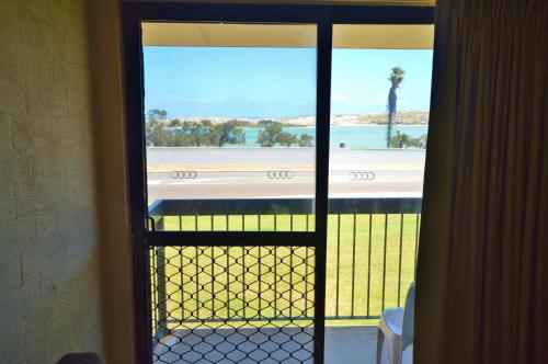 eine Tür zu einem Balkon mit Blick auf den Strand in der Unterkunft Riverview Holiday Apartment 26 - Kalbarri WA in Kalbarri