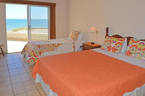 two beds in a room with a view of the ocean at Playa Romantica in Puerto Peñasco