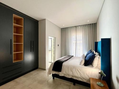 a bedroom with a large bed with blue pillows at Villa 206 Clarens Golf Estate in Clarens