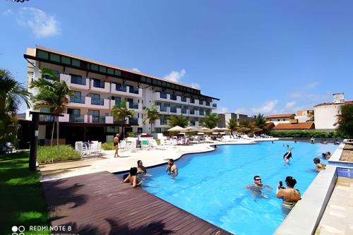 a group of people in the swimming pool at a hotel at Flat Super Confortável em Porto de Galinhas in Porto De Galinhas