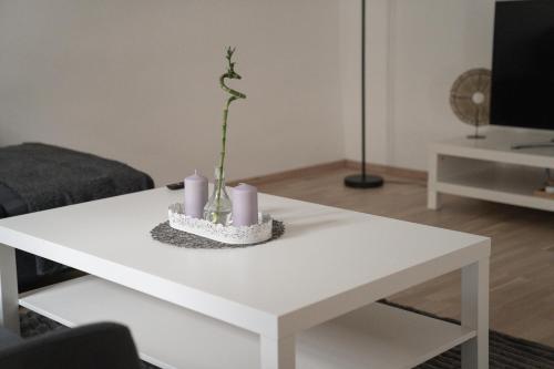 a white coffee table with candles and a plant on it at Beautiful Central City Apartment - 2BR, WIFI, Netflix & PS4 in Klosterneuburg
