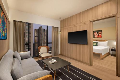 a living room with a couch and a bed at Moxy Mumbai Andheri West in Mumbai