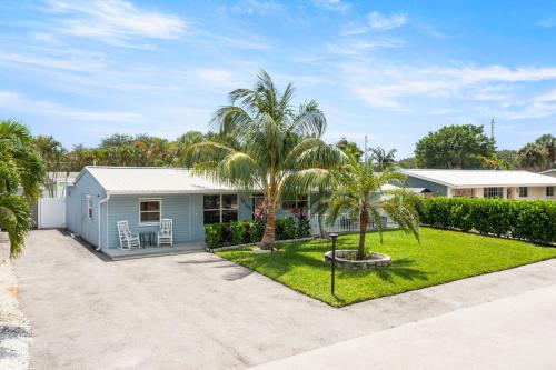 a blue house with palm trees in a yard at October Special! Limited-time Discount Book Now! in Jupiter