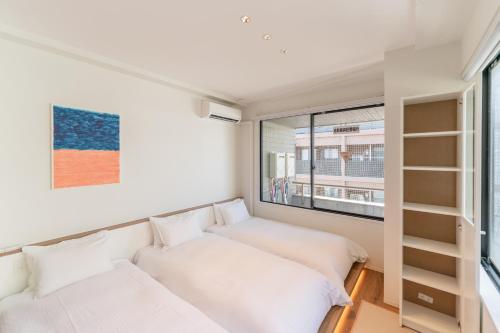a bedroom with two beds and a window at Flower Base HIMAWARI in Fukuoka