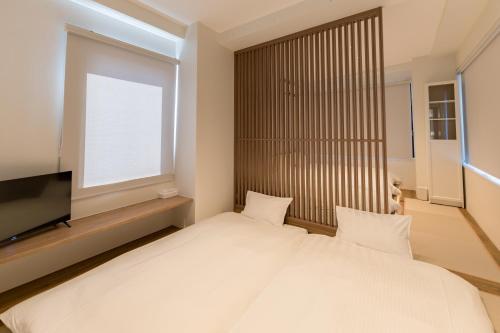 a bedroom with a large white bed and a television at Flower Base HIMAWARI in Fukuoka
