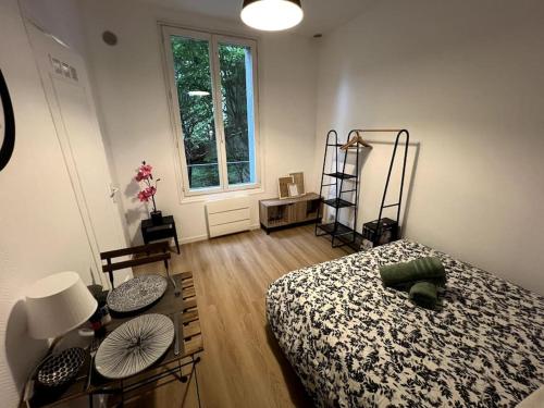 a bedroom with a bed and a table and a window at Studio Arcueil, maisons des examens, ligne 14, proche Paris in Arcueil