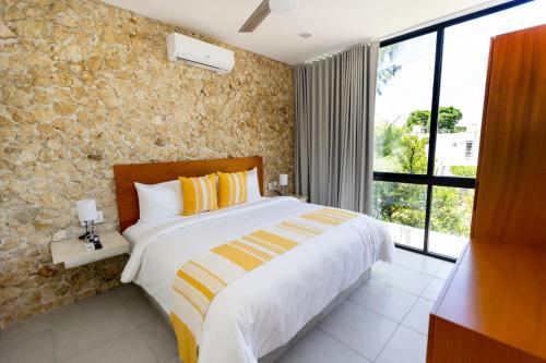 a bedroom with a bed and a stone wall at Casa Itzae Hotel Boutique in Mérida