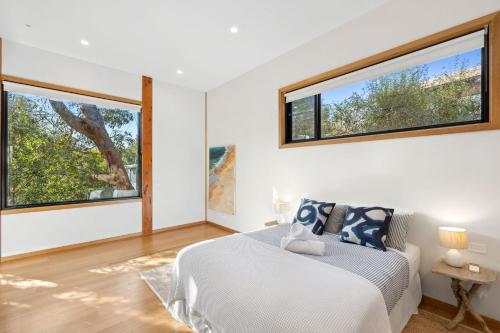 Un dormitorio con una cama y dos grandes ventanales. en Carji, en Anglesea