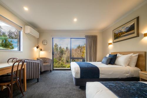 una camera d'albergo con due letti e una scrivania di Wanaka Top 10 Holiday Park a Wanaka