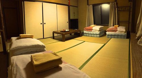 a room with two beds and a table in it at Kiyotaki Ryokan in Hikone