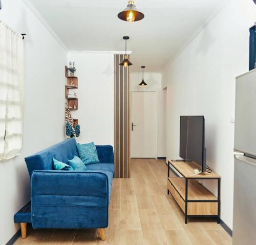 a living room with a blue couch and a tv at Maroni Oasis in Saint-Laurent du Maroni