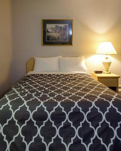 a bedroom with a bed with a black and white comforter at Perfect Inns & Suites in Weyburn