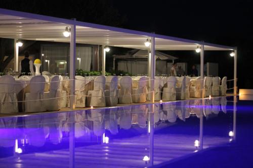 a group of white tables and chairs in front of a pool at Valle di Mare Country Resort in Fontane Bianche