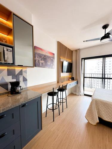 a bedroom with a bed and a kitchen with stools at Blue Apto Automatizado Moderno in São Paulo