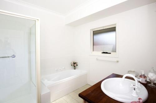 a white bathroom with a tub and a sink at Queen Street Cottage - By Berry Getaways in Berry