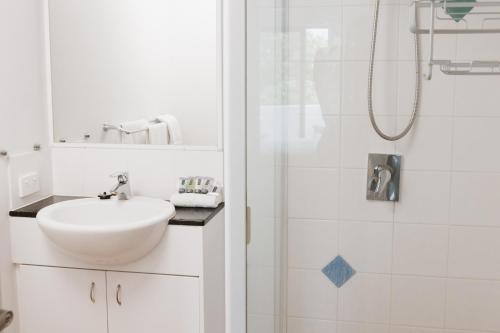 un bagno bianco con lavandino e doccia di Marcoola Beachside Resort a Marcoola