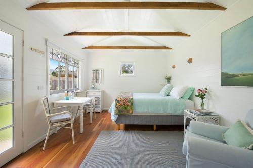 a bedroom with a bed and a table and a bed and a couch at Fremily Cottage - By Berry Getaways in Berry