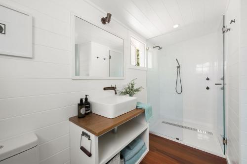 a white bathroom with a sink and a shower at Fremily Cottage - By Berry Getaways in Berry