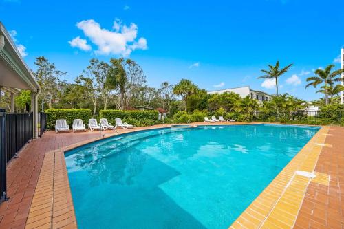 a swimming pool with chairs and a house at Marcoola Beachside Resort in Marcoola