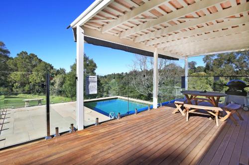 a wooden deck with a table and a swimming pool at Kiah - By Berry Getaways in Berry
