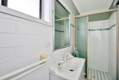a white bathroom with a sink and a shower at Floriel - By Berry Getaways in Berry