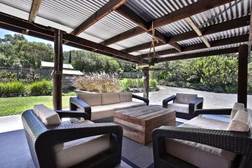 a patio with furniture and a wooden pergola at Amaroo House - By Berry Getaways in Berry