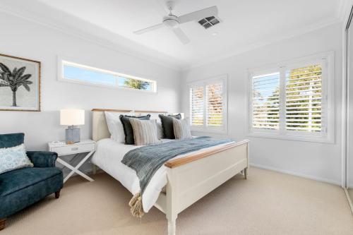 a white bedroom with a bed and a blue couch at Berry Vista - By Berry Getaways in Berry