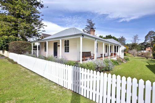 a white house with a white picket fence at The Cottage - By Berry Getaways in Berry